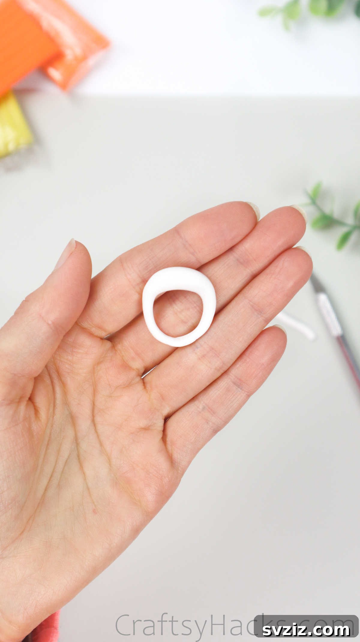 Crafting Your Own Clay Rings Effortlessly 23 A hand holding the white polymer clay ring, now with its ends joined and the central bump prominent