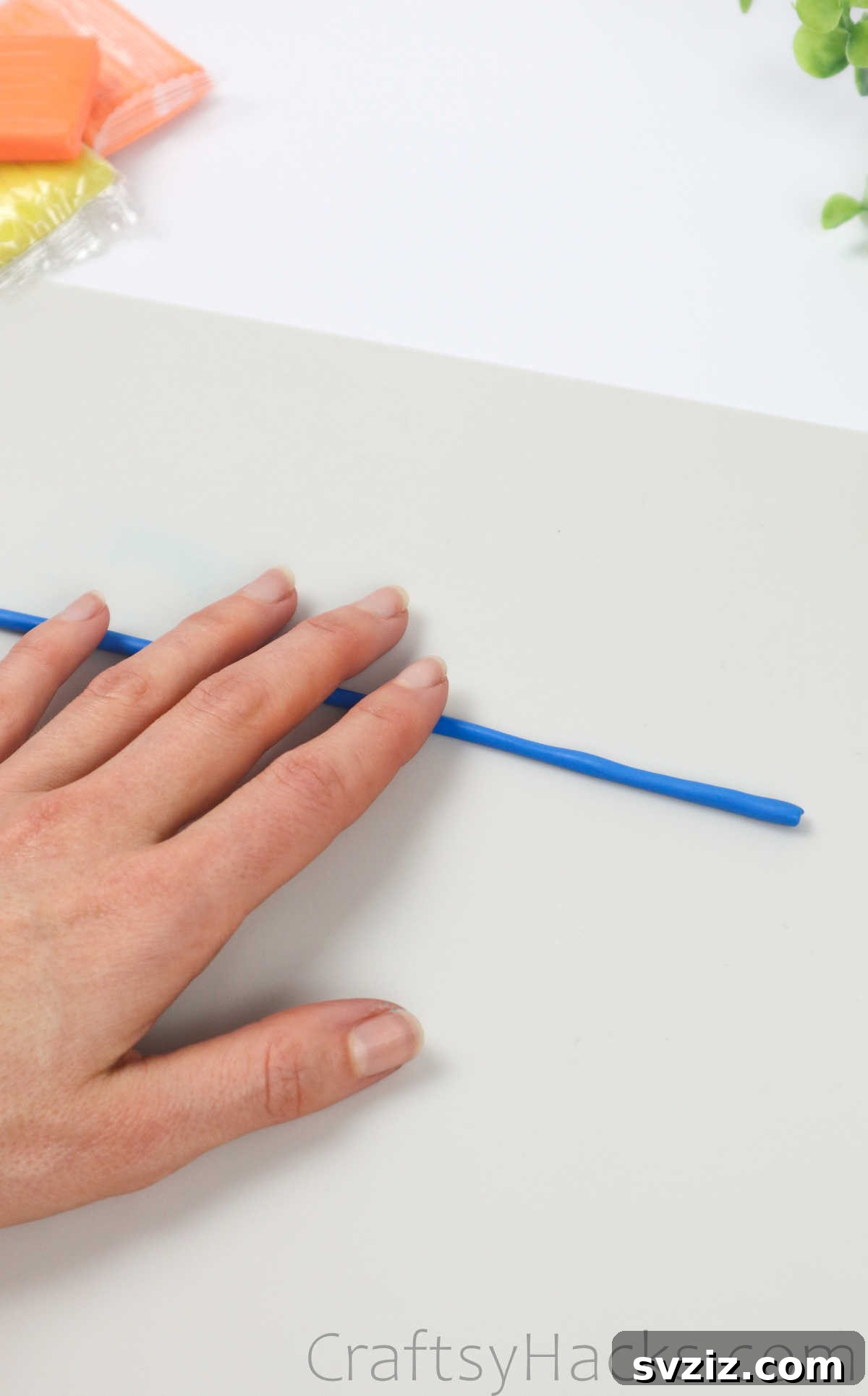 Crafting Your Own Clay Rings Effortlessly 7 A hand gently rolling out blue polymer clay into a long, thin strand on a flat surface