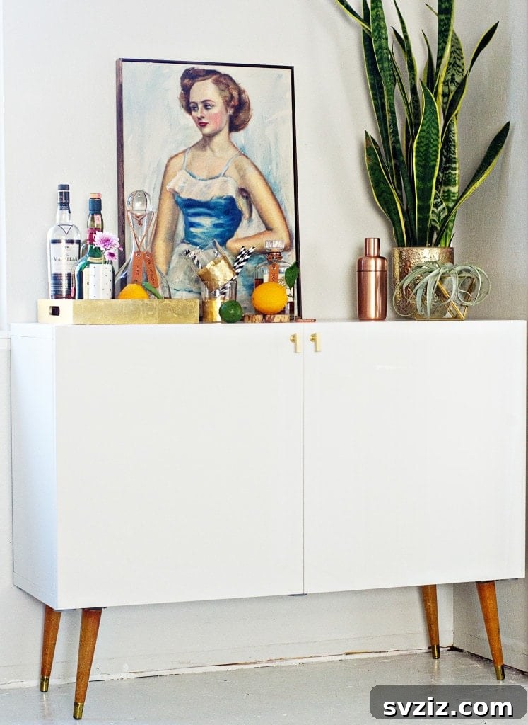 20 Game-Changing IKEA Kitchen Hacks 12 Mid-century bar cabinet hack using an IKEA cabinet with custom knobs and gold foil interior