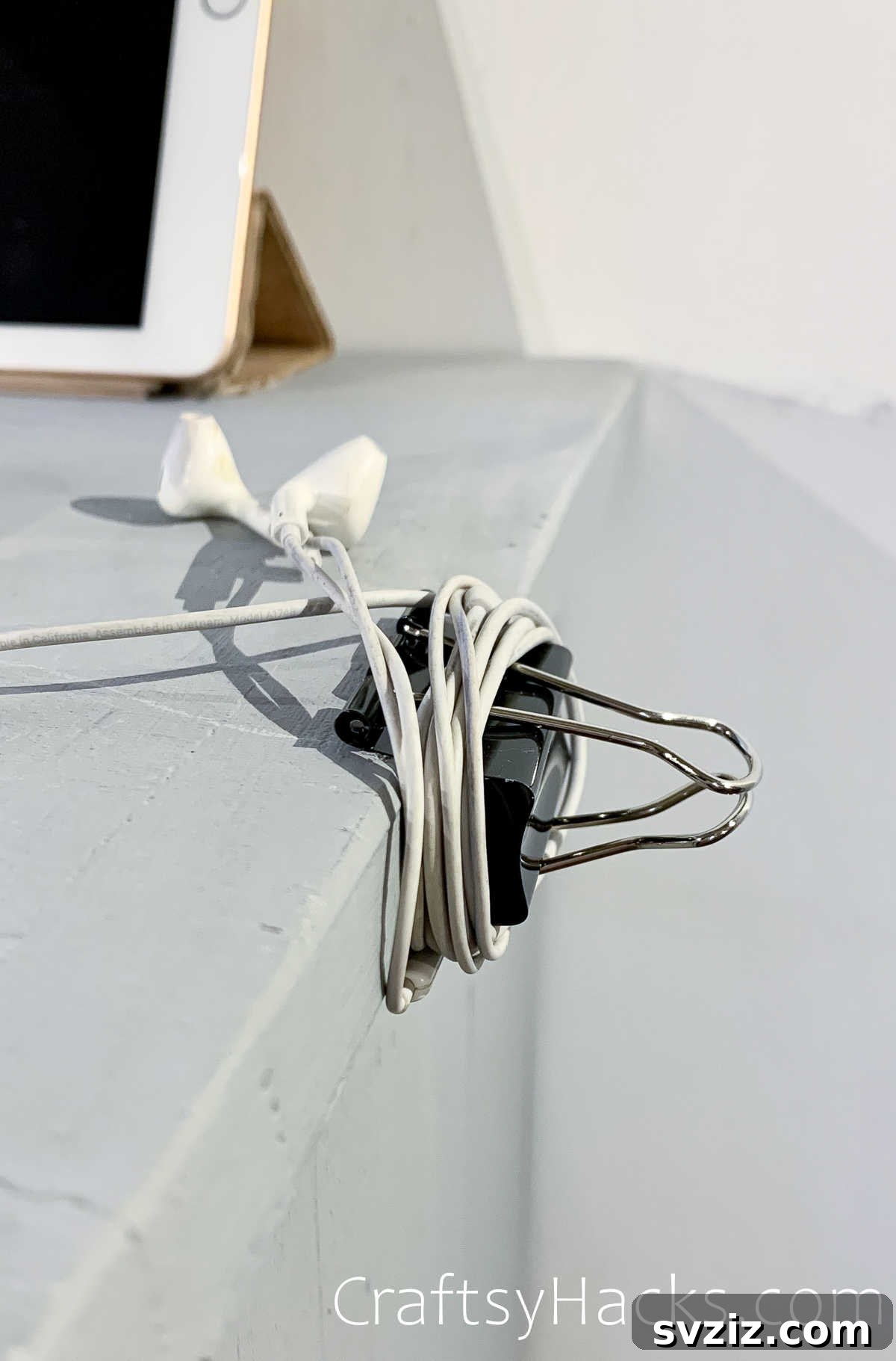 Earbuds neatly wrapped around a binder clip to prevent tangles