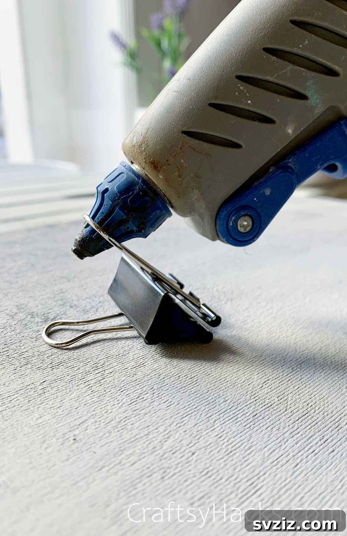 Binder clip used as a makeshift stand for a hot glue gun to prevent mess