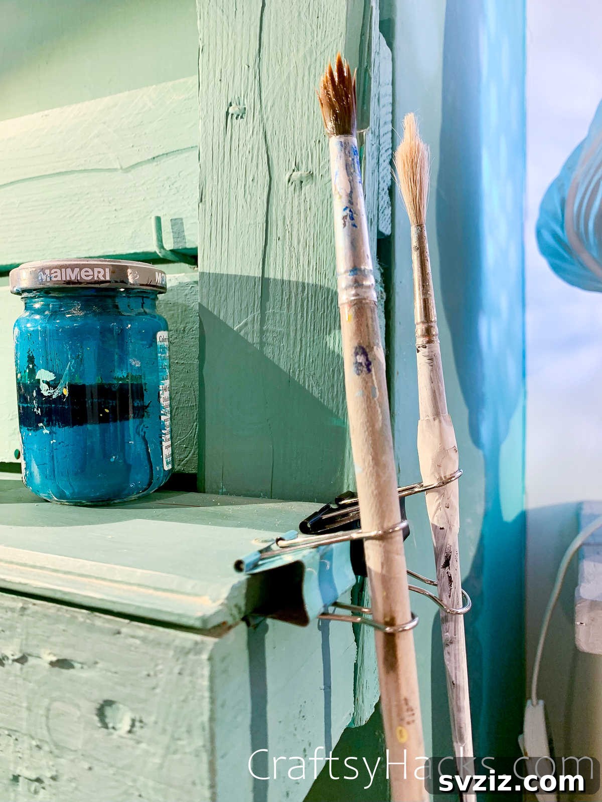 Binder clip attached to a paint brush to hang it on a workstation