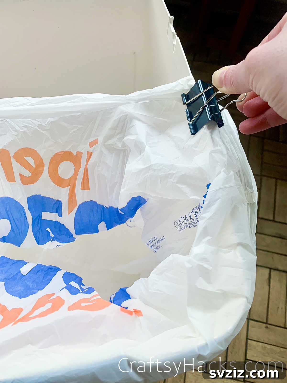 Holding trash bags securely in a bin with a binder clip