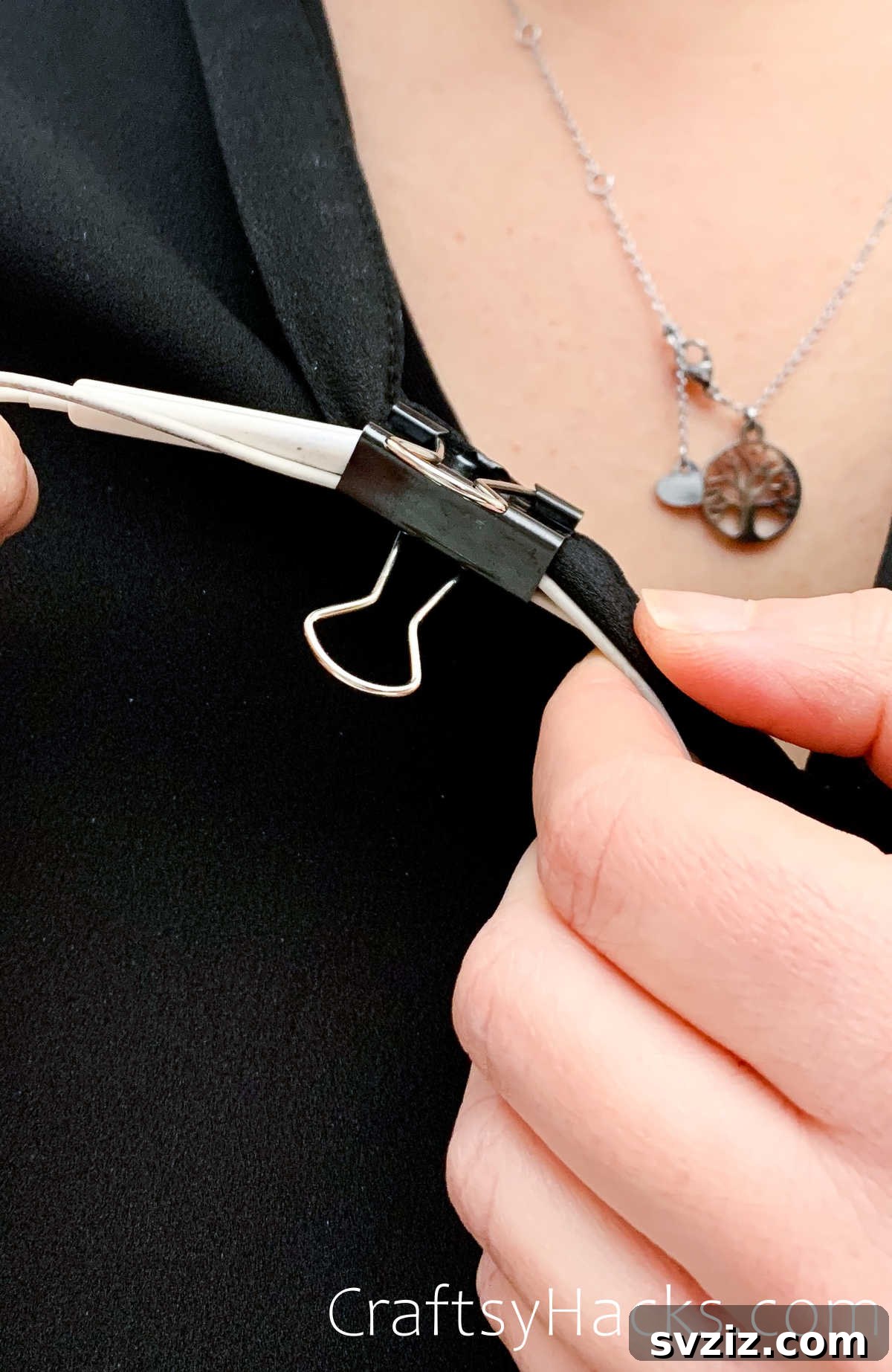 Binder clip securing wired earbuds to clothing
