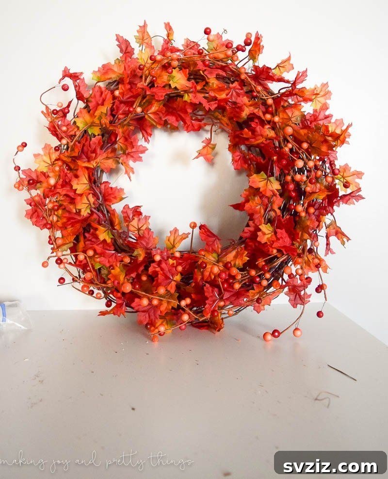 A festive DIY traditional fall wreath adorned with artificial autumn leaves, berries, and a rustic bow, creating a welcoming entrance decor.