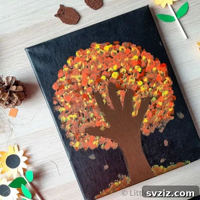 A colorful handprint fall tree artwork, created with multiple handprints in red, orange, and yellow to represent autumn leaves on a tree trunk.