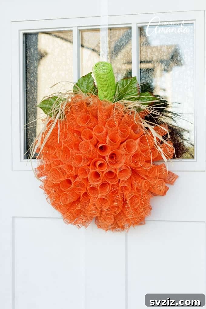 A vibrant deco mesh pumpkin wreath, crafted with orange and green mesh, adorned with fall ribbons and a pumpkin accent, ideal for autumn front door decor.