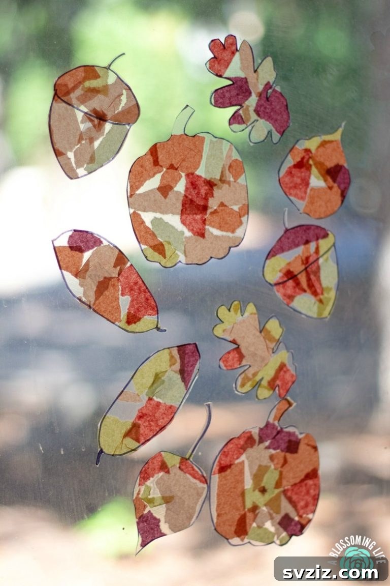 Vibrant fall suncatcher craft for kids, made with colorful tissue paper leaves, perfect for window display and light play.