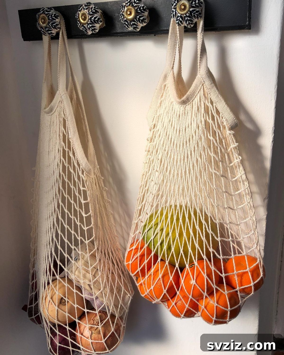 Hang net bags for fruits and vegetables from hooks or doorknobs to save counter and pantry space in a small kitchen.