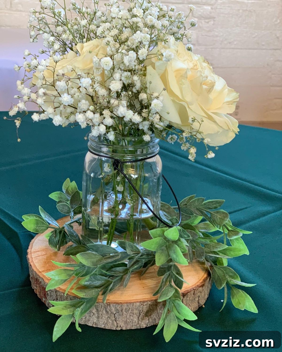 27 Elegant Round Table Wedding Centerpiece Inspirations 13 Forest-themed wedding centerpiece with florals in Mason jars and tree bark holders.