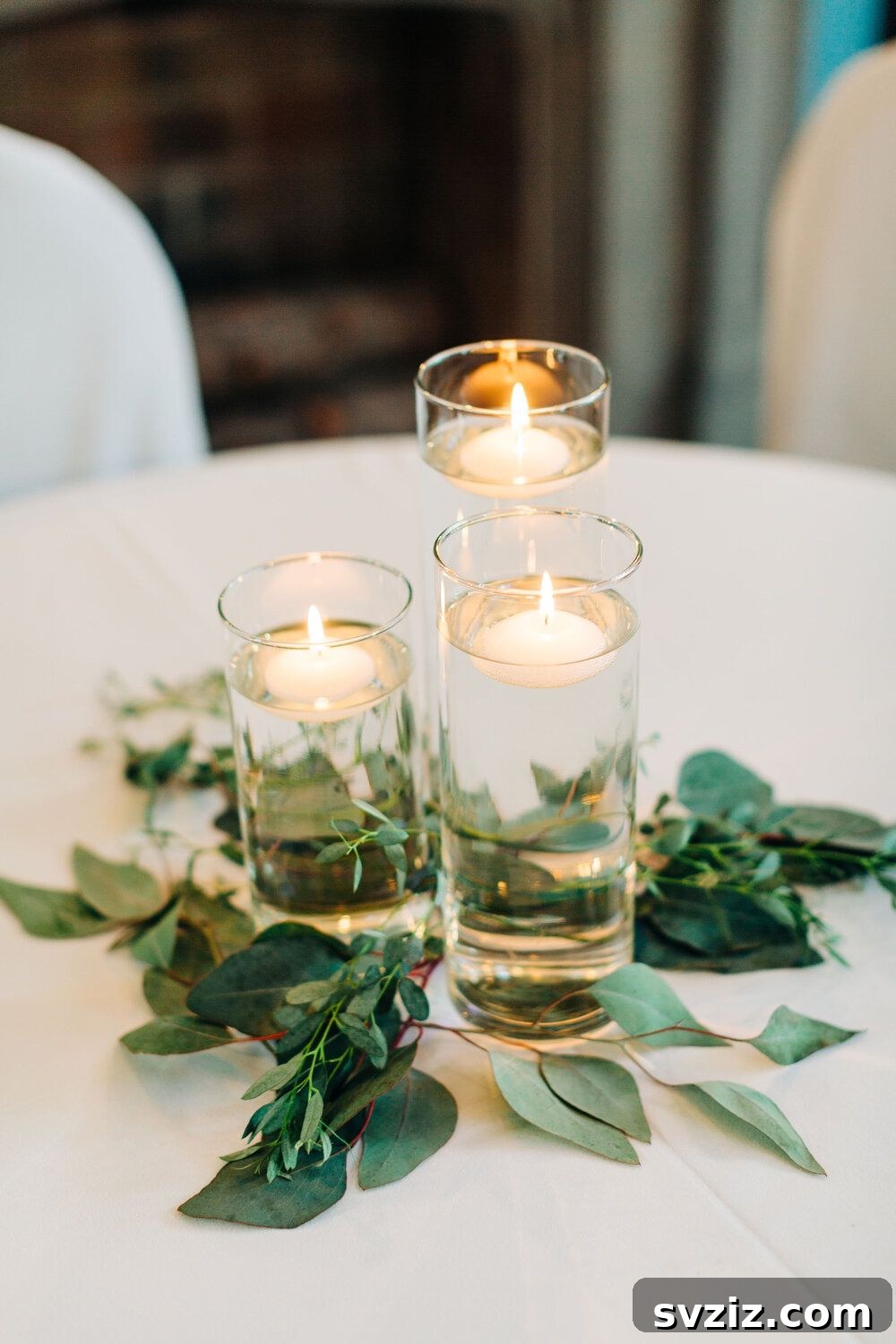27 Elegant Round Table Wedding Centerpiece Inspirations 16 Magical wedding decor with floating candles in glass vases surrounded by lush greenery.