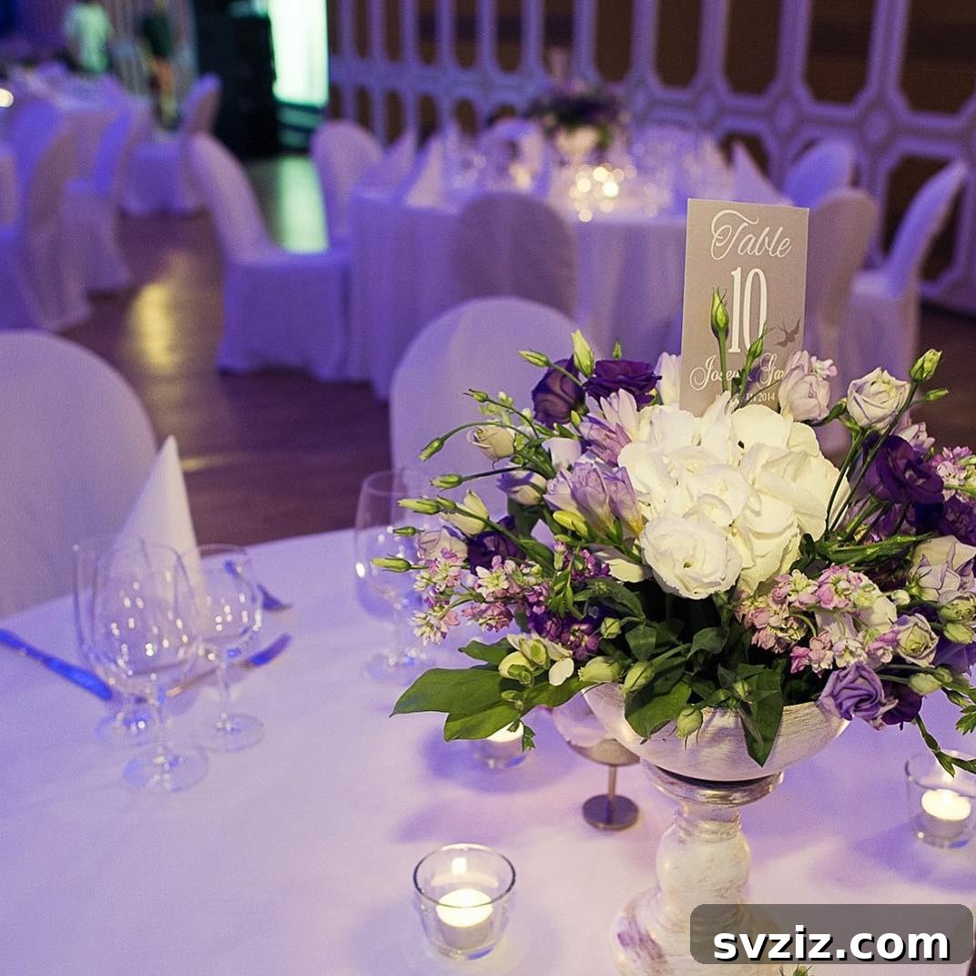27 Elegant Round Table Wedding Centerpiece Inspirations 19 Purple and white floral centerpiece integrated with a table number holder for a cohesive wedding look.