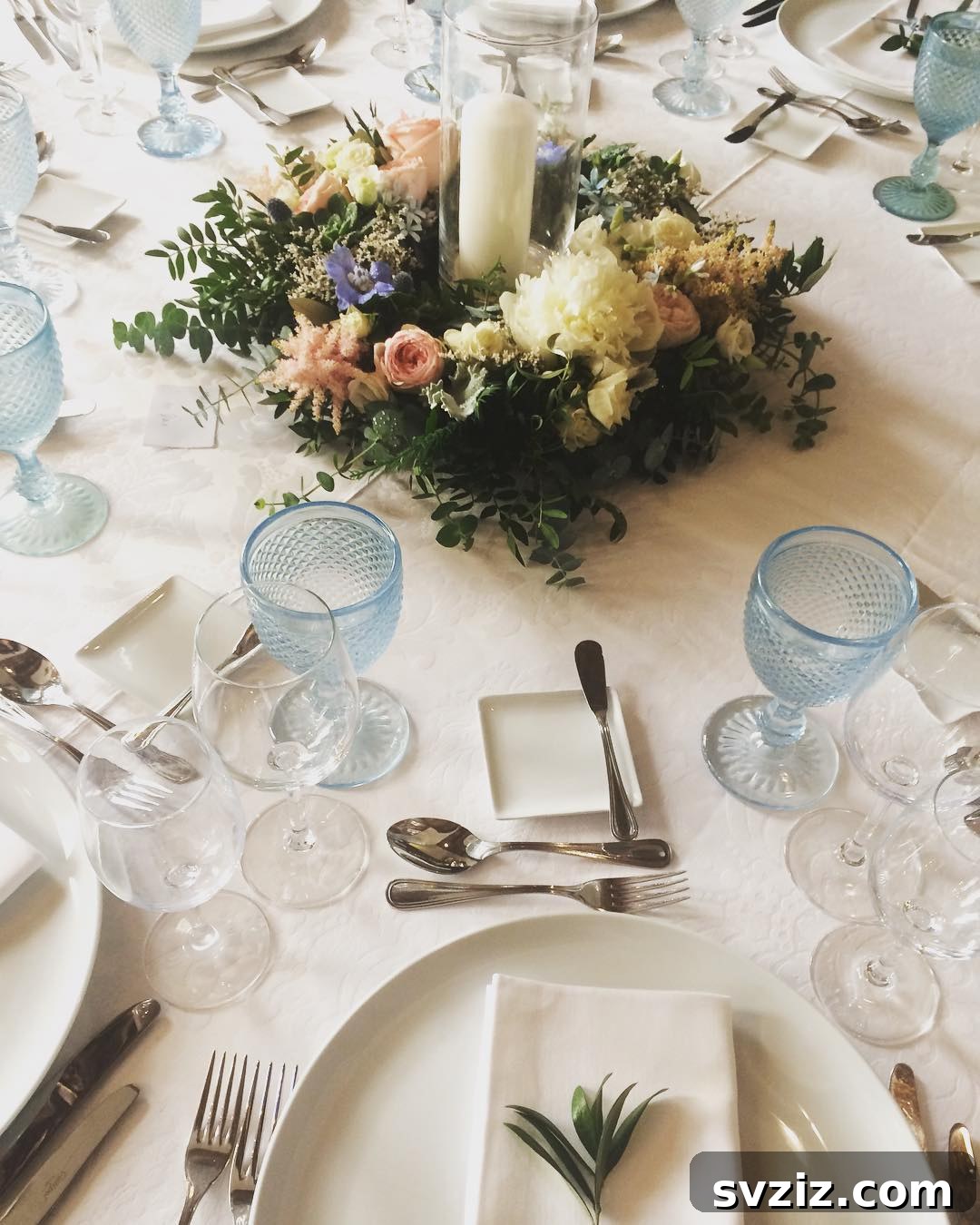 27 Elegant Round Table Wedding Centerpiece Inspirations 3 Elegant wedding centerpiece featuring a floral wreath with a tall pillar candle in hurricane glass.