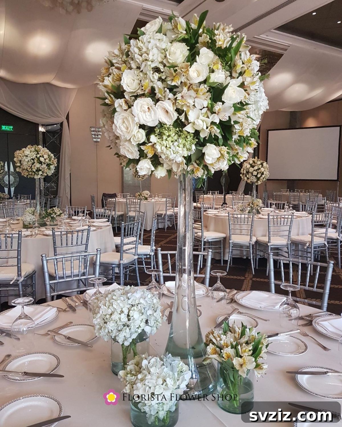 27 Elegant Round Table Wedding Centerpiece Inspirations 22 Wedding table centerpiece with an extra tall floral arrangement surrounded by smaller mini arrangements.