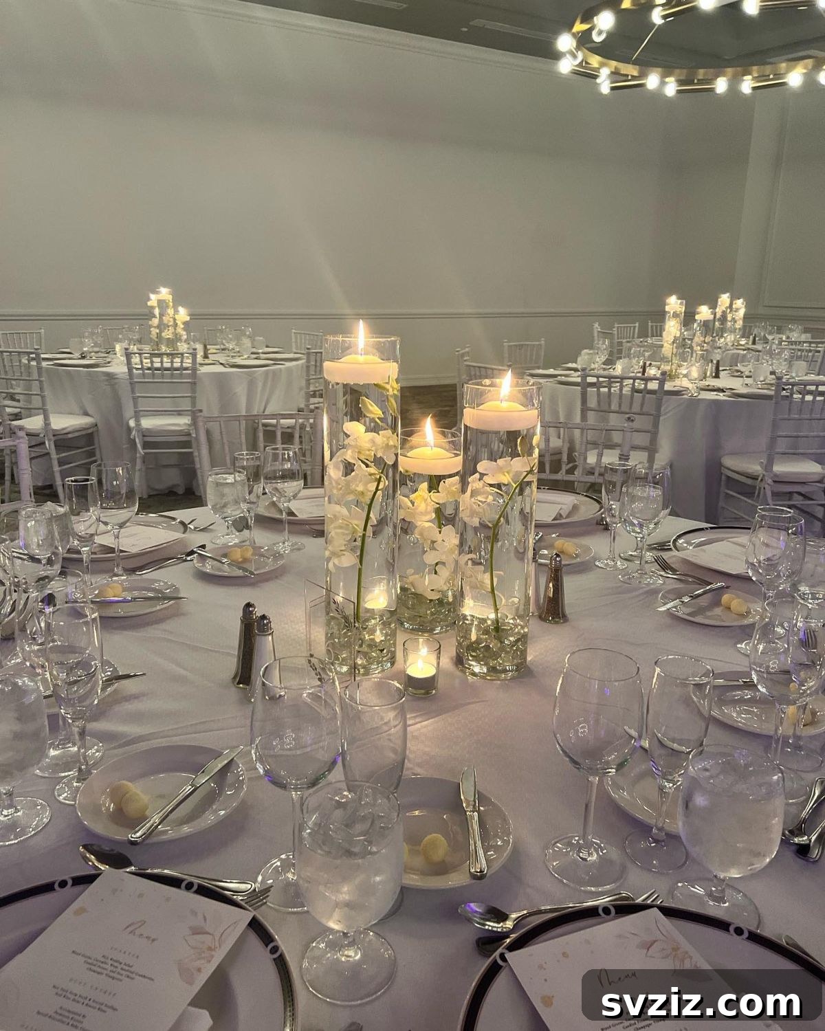 27 Elegant Round Table Wedding Centerpiece Inspirations 7 Magical wedding centerpiece featuring white orchids in glass cylinders with floating candles.