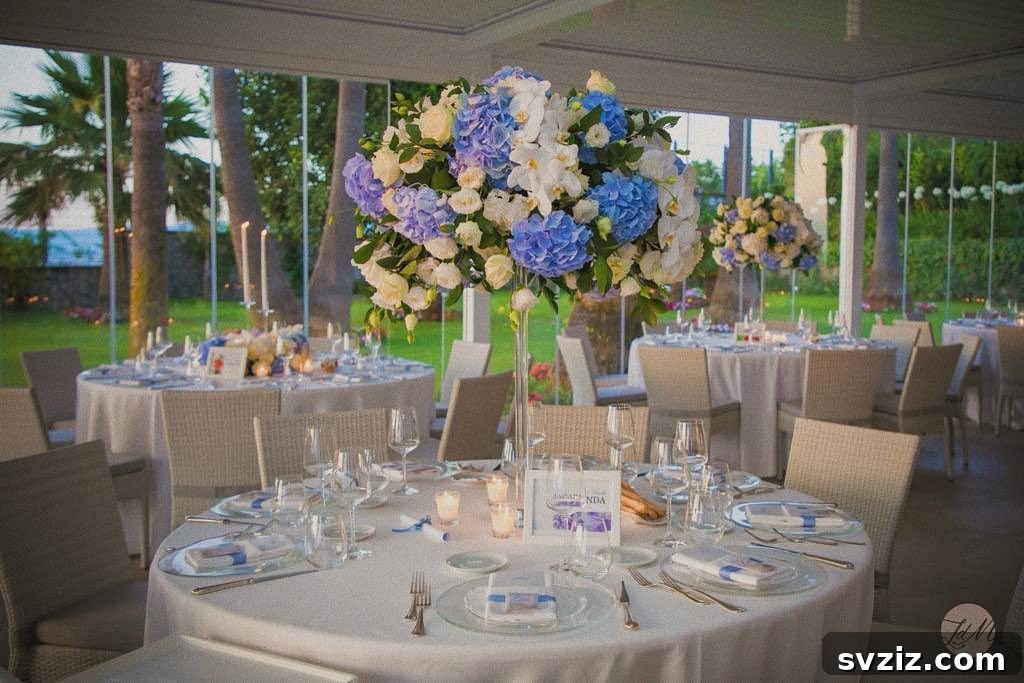 27 Elegant Round Table Wedding Centerpiece Inspirations 8 Grand tall floral arrangement in an Eiffel Tower vase, elevating wedding decor.