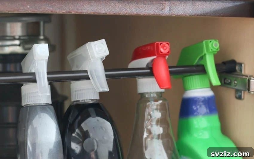 A tension rod installed under a kitchen sink, used to hang spray bottles, optimizing vertical storage space.