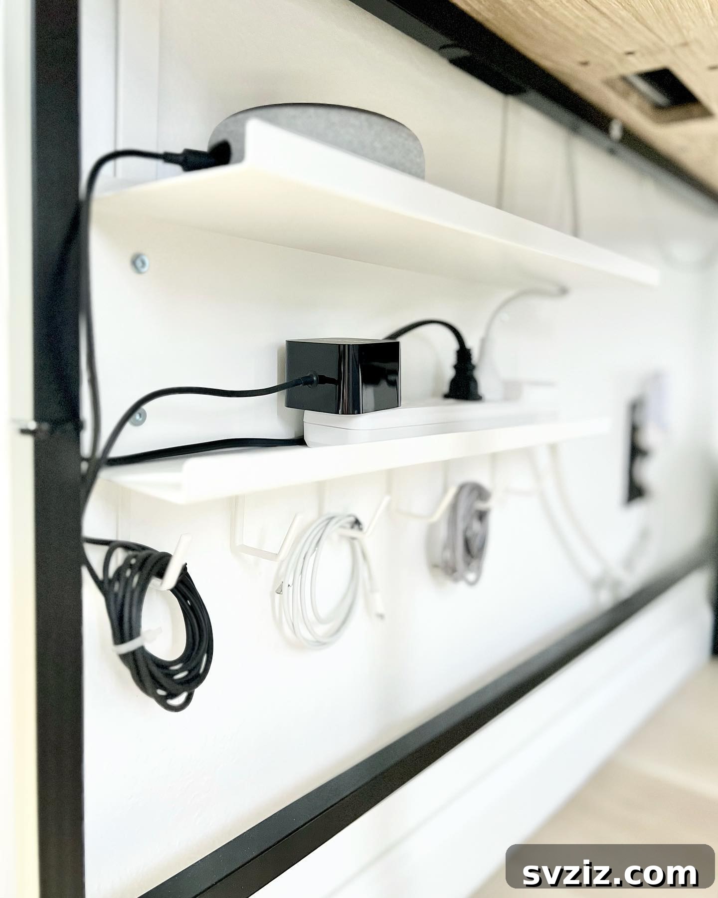 A wall-mounted cable storage rack neatly organizing looped cables and power boxes, creating a clean tech setup.