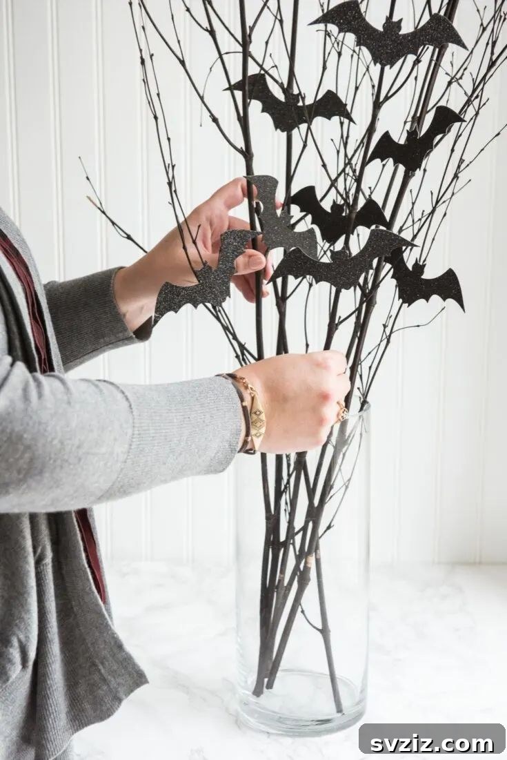 31 Terrifying Halloween Bash Concepts 18 DIY bat branch centerpiece with black bats and silver glitter