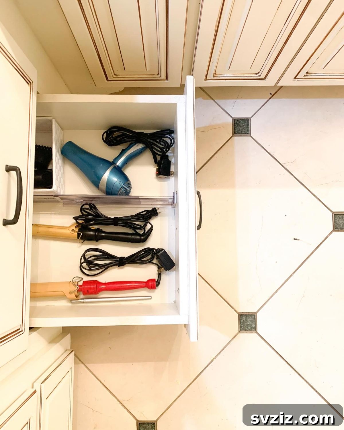 27 Smart Solutions for Organizing Clutter 15 Dedicated Bathroom Appliance Drawer - A bathroom drawer designed with compartments to neatly store hair styling tools such as a hairdryer, straightener, and curling iron, with cords managed.