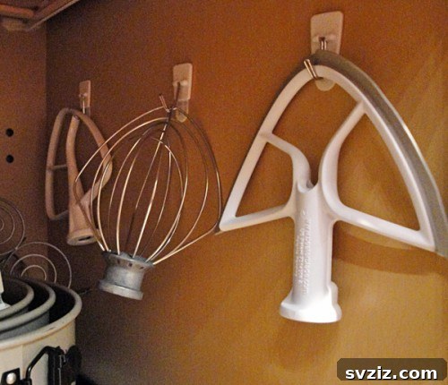 Kitchen mixer attachments hung neatly on adhesive hooks inside a cabinet door