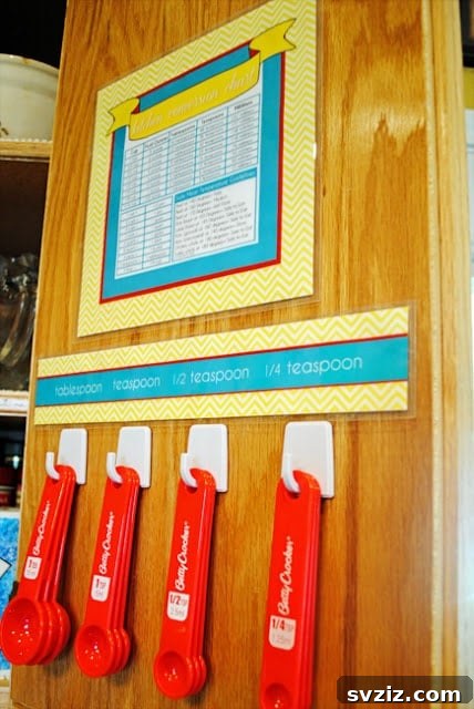 Measuring spoons neatly organized on self-adhesive hooks inside a kitchen cabinet door