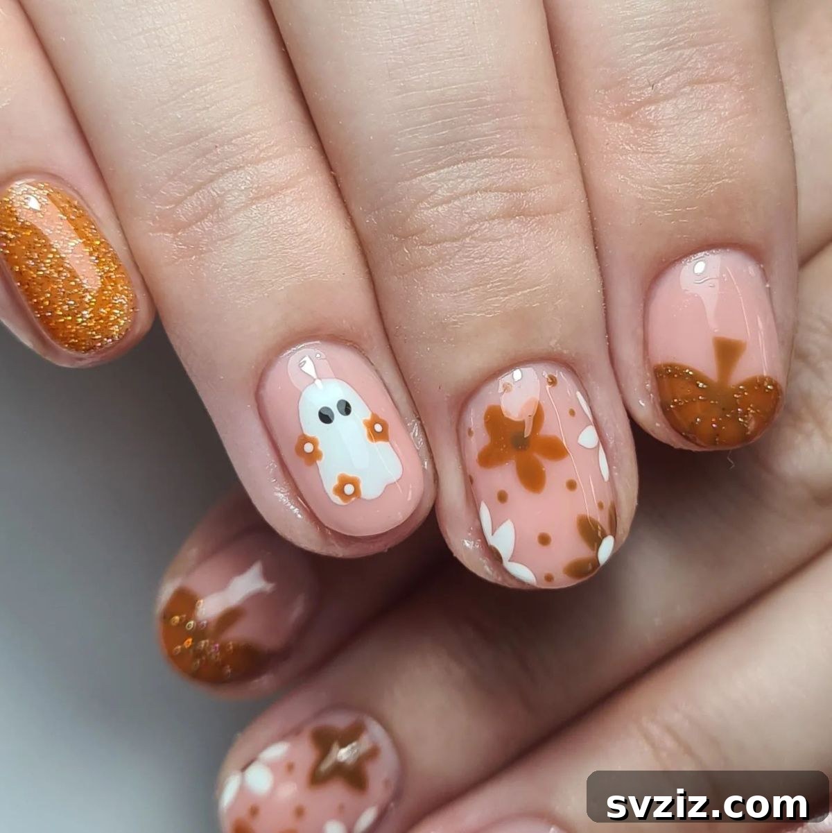 Cute Halloween themed nail art with ghosts, pumpkins, and fall leaves