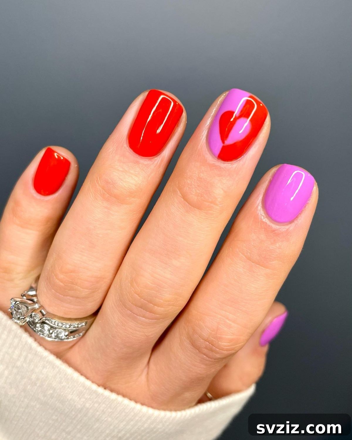 Valentine's Day nail art with hearts and pink/red colors on short nails