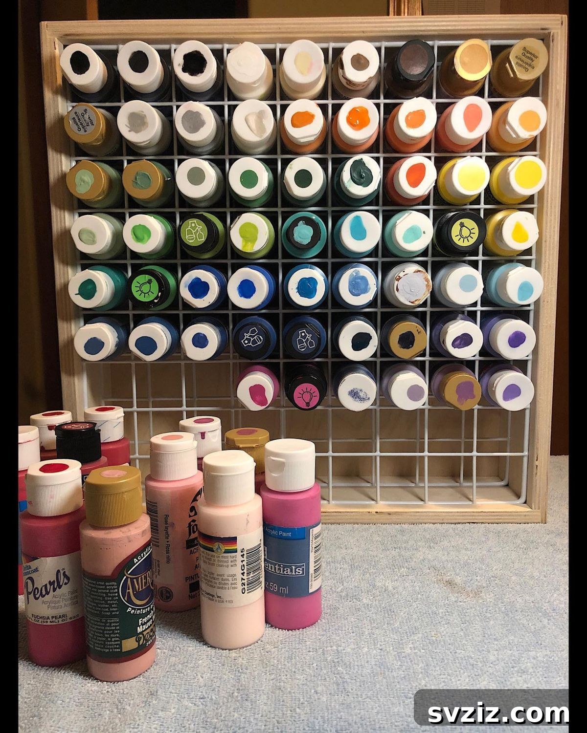 Unlock Creativity: Smart Organization for Your Art Studio 11 A metal grid paint rack organizing acrylic paint tubes, with color samples painted on each lid for easy identification. This space-saving storage solution fits perfectly into square shelves, providing an efficient and visually appealing way to manage art paint supplies.