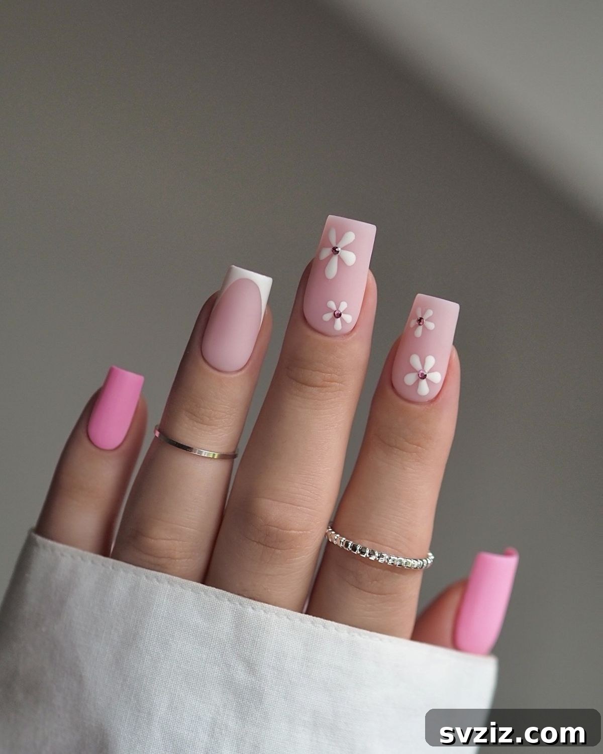31 Chic Short Matte Nail Designs to Try Now 3 Short matte nails with delicate pink and white floral designs and a single French tip.