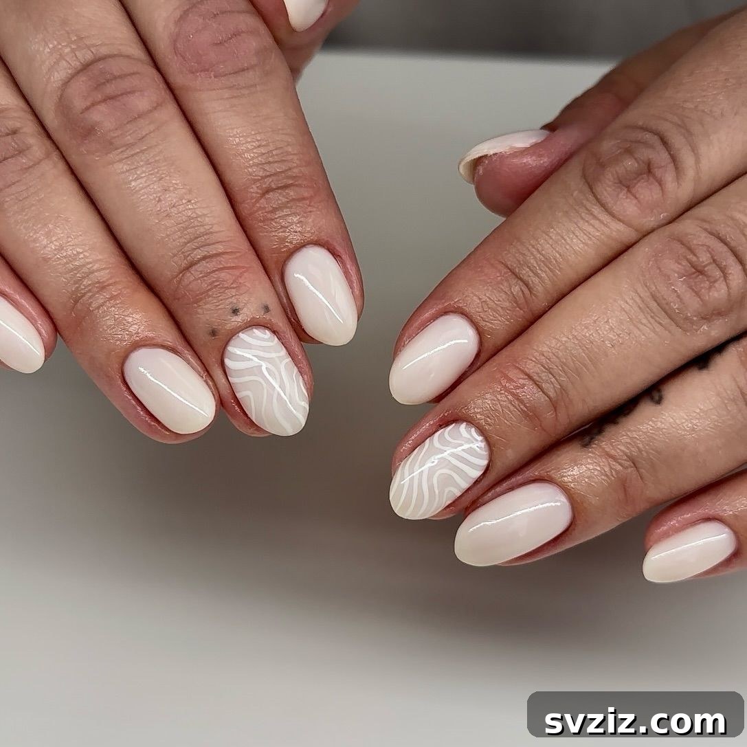 41 Effortless Nude Nail Ideas for Everyone 25 Soft white nude nails with intricate accent designs, creating a delicate and must-try manicure.