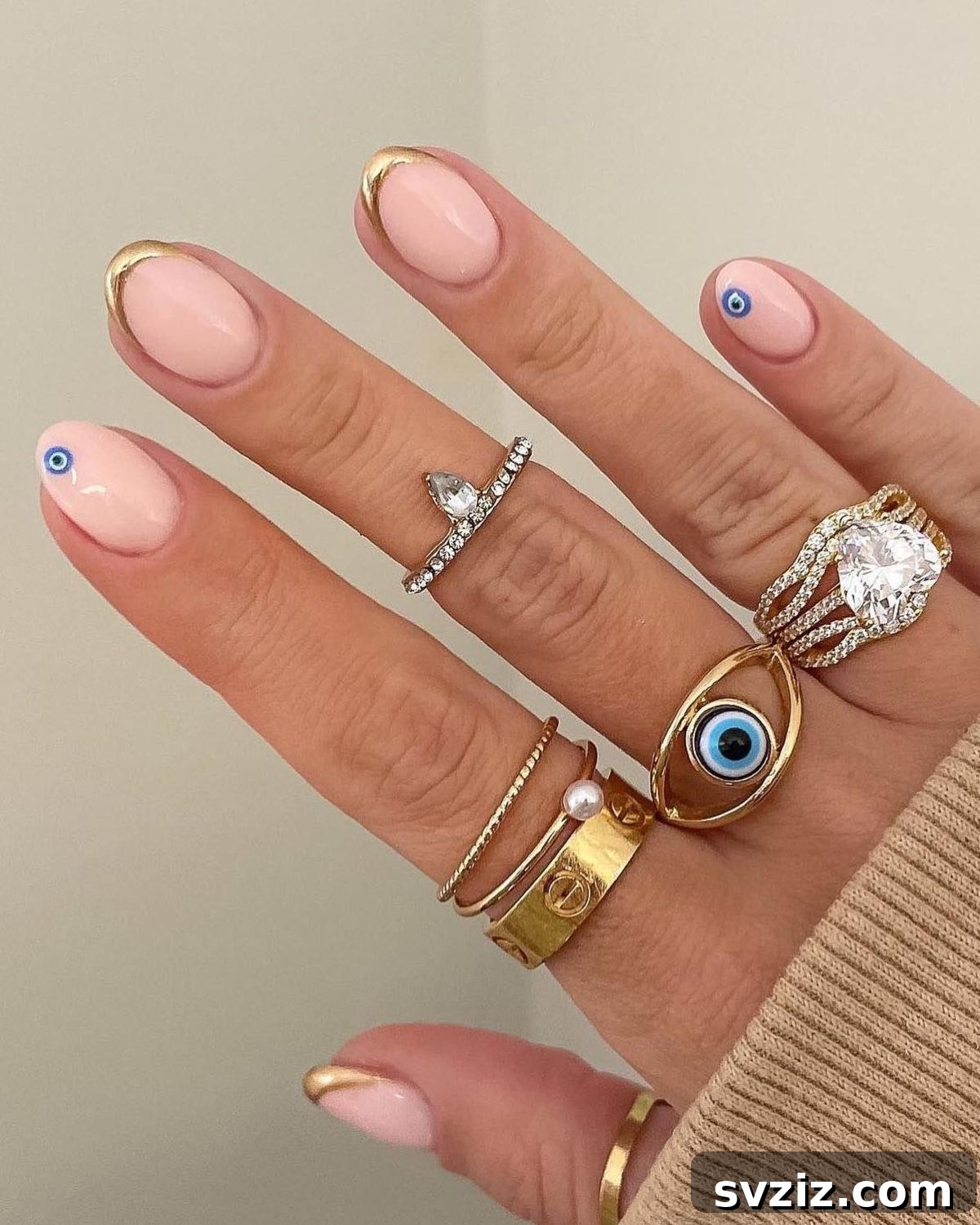41 Effortless Nude Nail Ideas for Everyone 37 Stylish evil eye nail design on nude nails with shimmering gold tips, combining mystic charm with modern elegance.