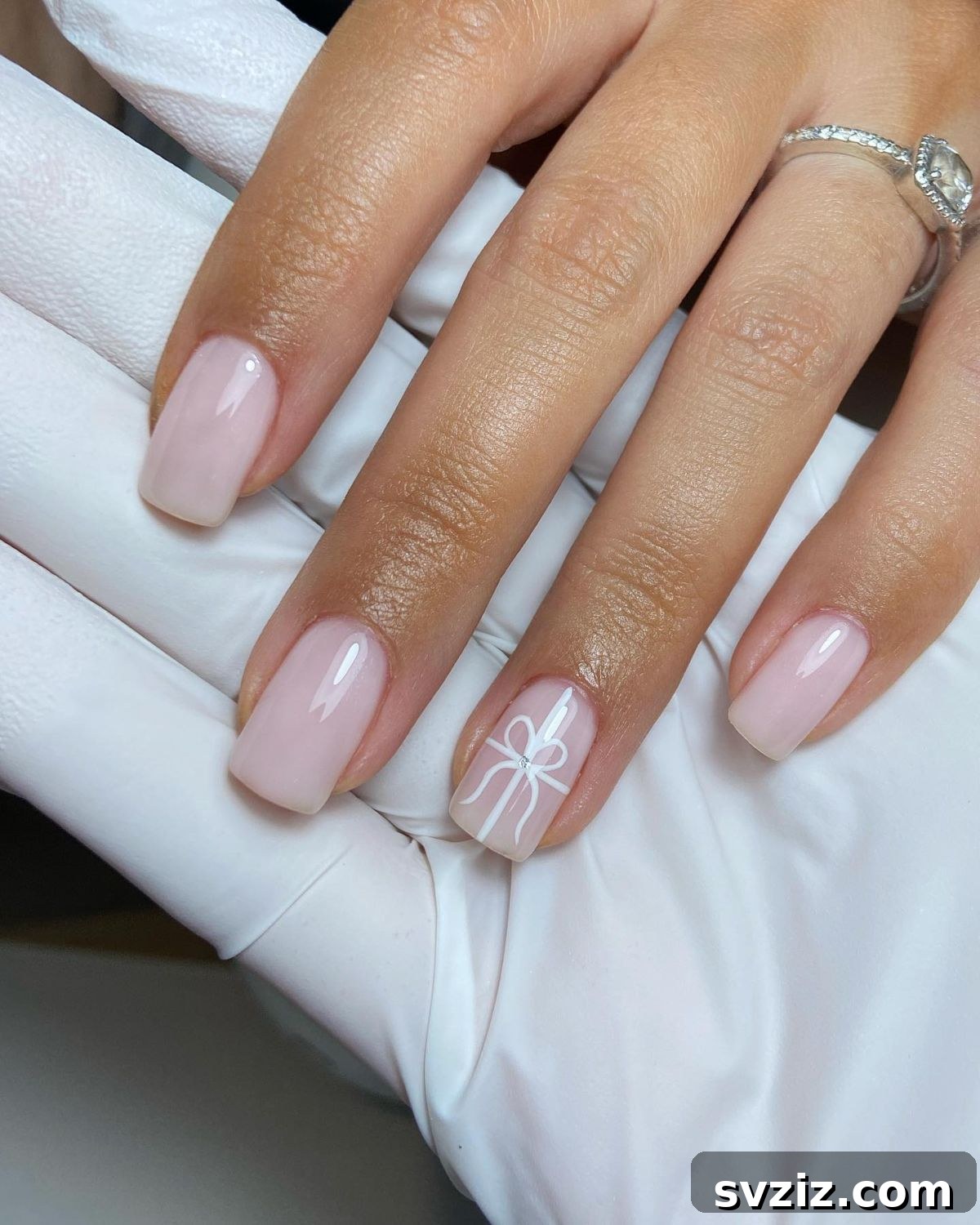 41 Effortless Nude Nail Ideas for Everyone 8 Charming Christmas bow accent nail on a nude base, perfect for festive holiday manicures.