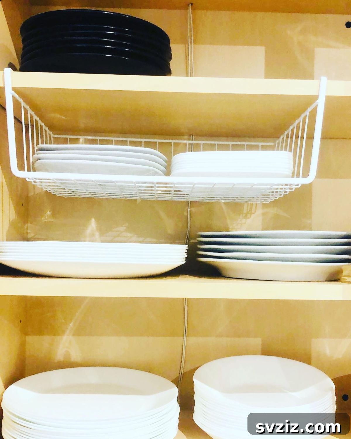Smart Plate Organization Ideas for a Perfectly Tidy Kitchen 4 Under-shelf wire basket holding small plates and bowls, creating additional storage in a kitchen cabinet.