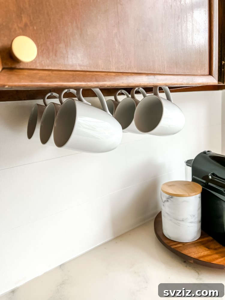 13 Genius Ways to Organize Your Sink Area 11 Mugs neatly hung under a kitchen cabinet, saving counter space and creating a designated coffee station.