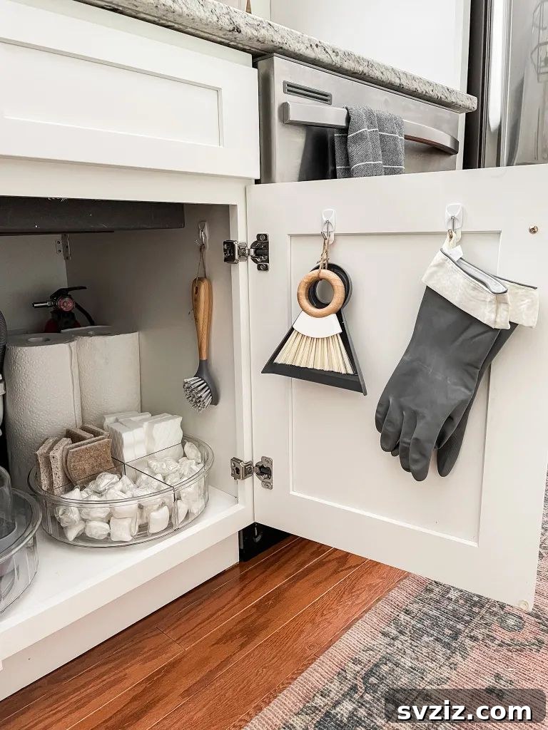 13 Genius Ways to Organize Your Sink Area 12 Command hooks holding cleaning brushes and gloves on the inside of a kitchen sink cabinet door, maximizing vertical storage.
