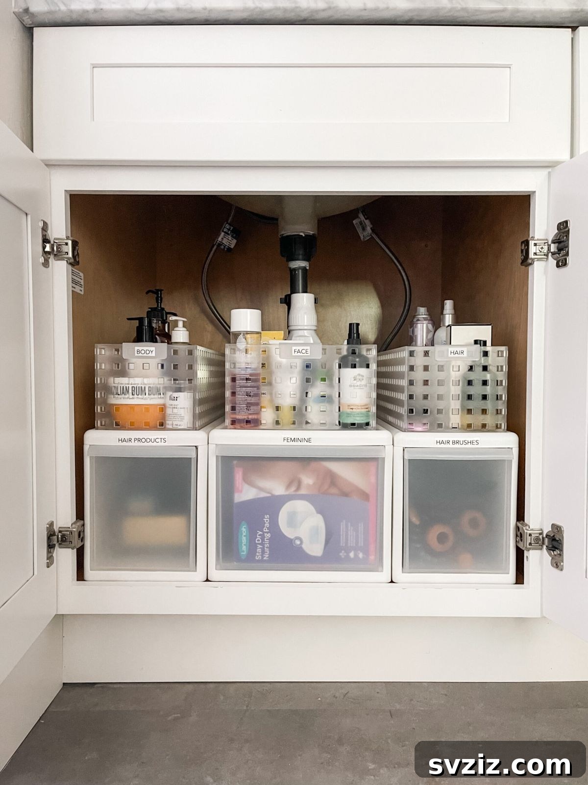 13 Genius Ways to Organize Your Sink Area 3 Clear containers organizing toiletries and cleaning products under a bathroom sink, promoting efficient under-sink storage.