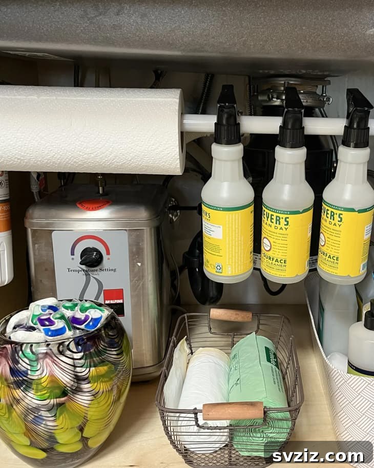 13 Genius Ways to Organize Your Sink Area 10 Tension rod installed under a kitchen sink to hang spray bottles, demonstrating clever vertical storage.