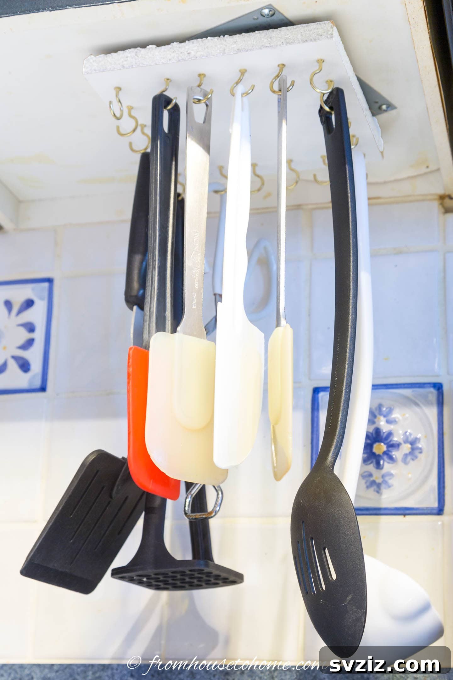 17 Smart Utensil Organizing Hacks 14 Under-cabinet hanging storage rack organizing various cooking utensils, maximizing vertical space in a kitchen