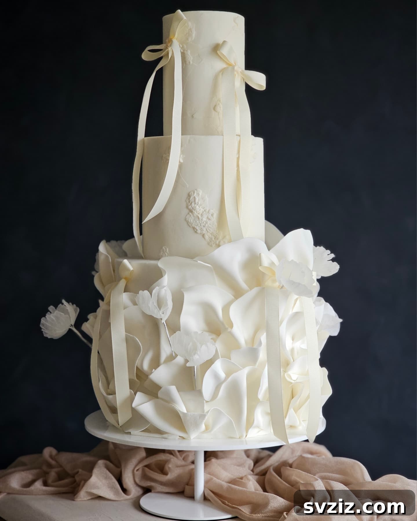 27 Elegant Wedding Cake Inspirations 13 A breathtaking multi-tier wedding cake with flawless layers, soft hues, and delicate lily floral accents, draped ribbons, and bows, symbolizing purity, devotion, and new beginnings.