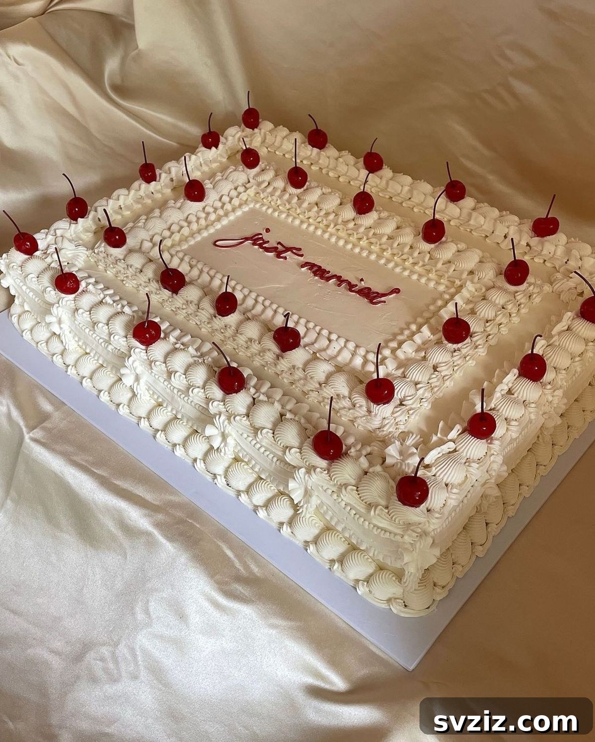 27 Elegant Wedding Cake Inspirations 16 A rectangular wedding cake combining fun and nostalgia, featuring beautifully piped white frosted layers, a 'Just Married' message, and luscious ruby-red cherries, perfect for a whimsical touch.