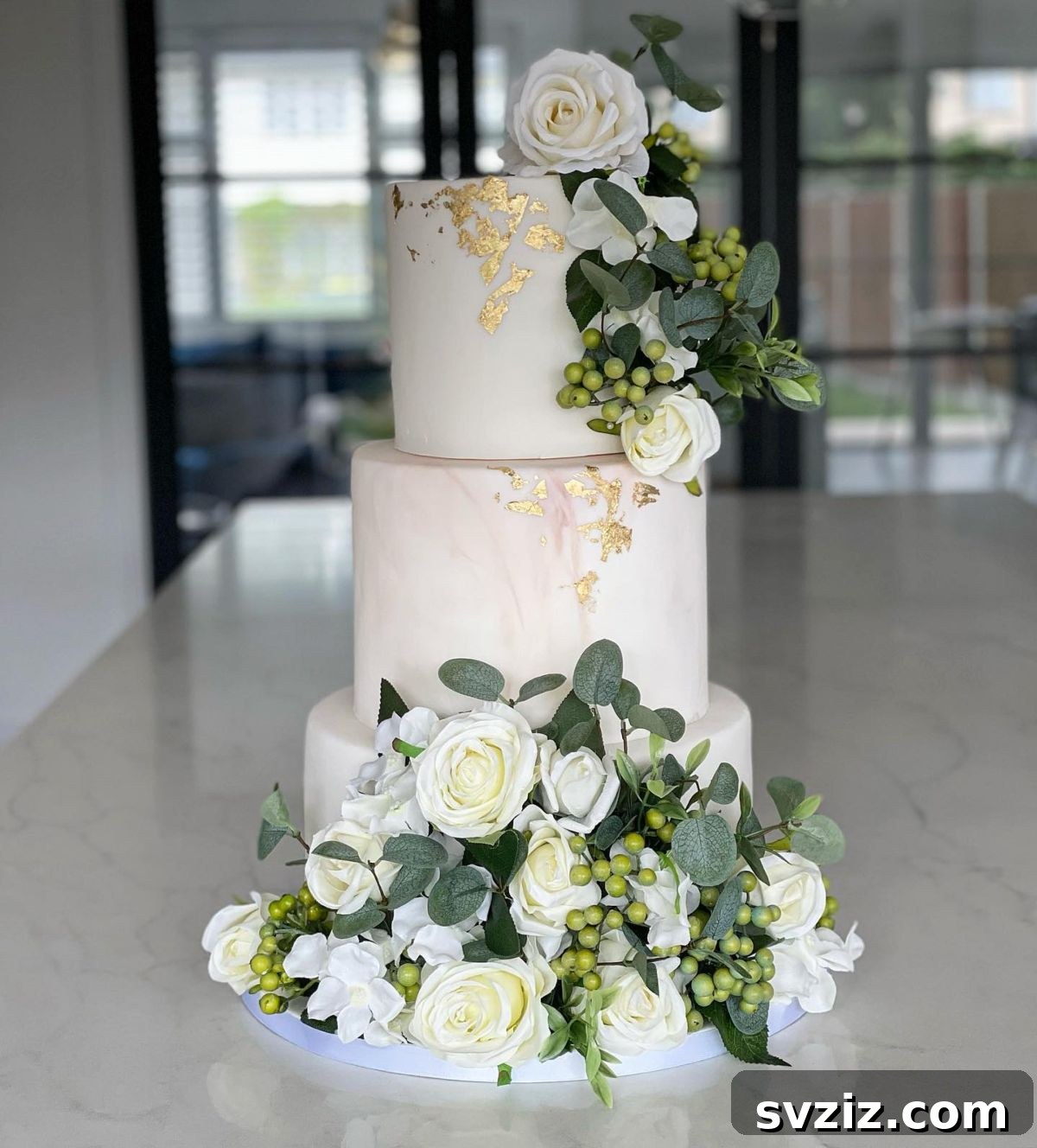 27 Elegant Wedding Cake Inspirations 21 An enchanting garden-inspired wedding cake cascading with white roses, entwined with greenery and tiny berries, featuring flecks of gold leaf and a hint of marble veins, creating a luxurious and artistic masterpiece.