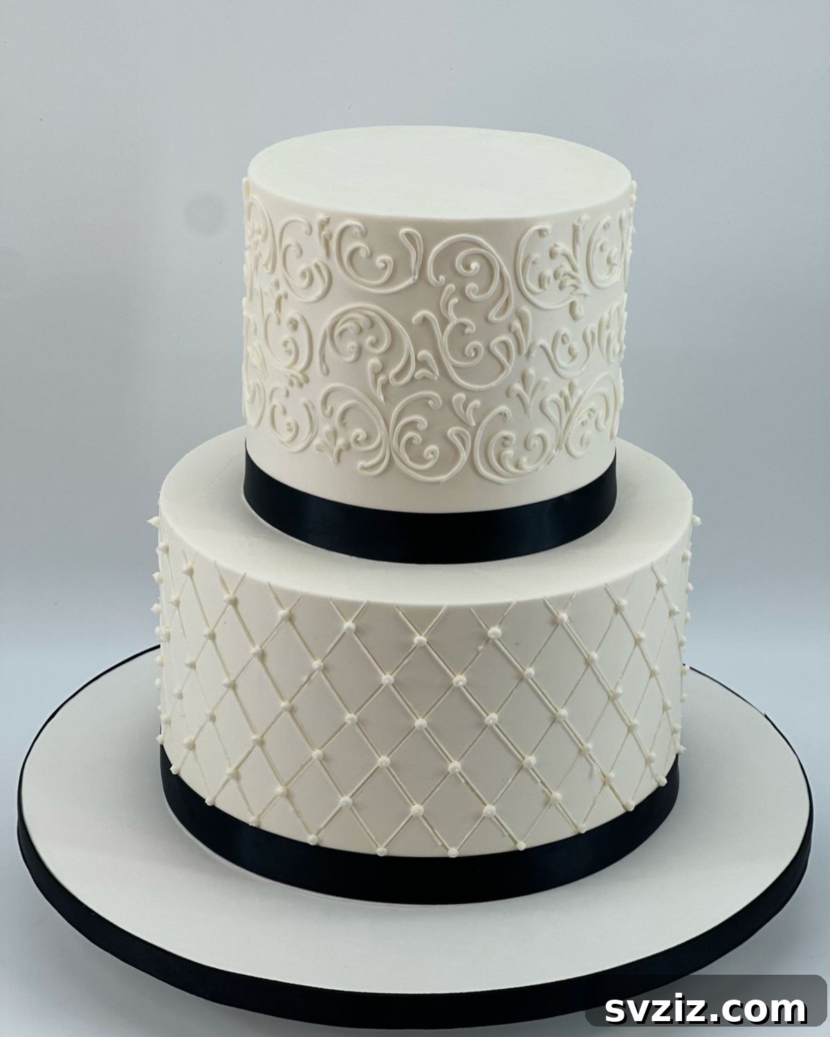 27 Elegant Wedding Cake Inspirations 22 A classy monochrome wedding cake showcasing timeless quilting, transforming tiers into a fabric-like texture with delicate pearls, contrasted with lovely scrollwork, mixing geometric precision with delicate swirling patterns.