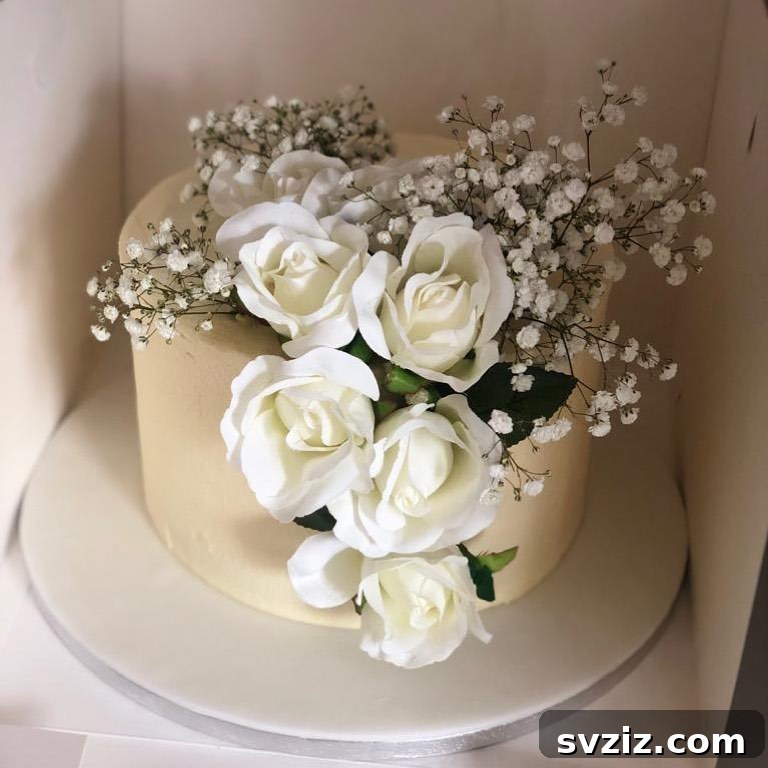 27 Elegant Wedding Cake Inspirations 24 A simple yet elegant single-tier wedding cake adorned with beautiful white roses, symbolizing purity, devotion, and everlasting love, perfect for a couple embarking on their beautiful journey together.