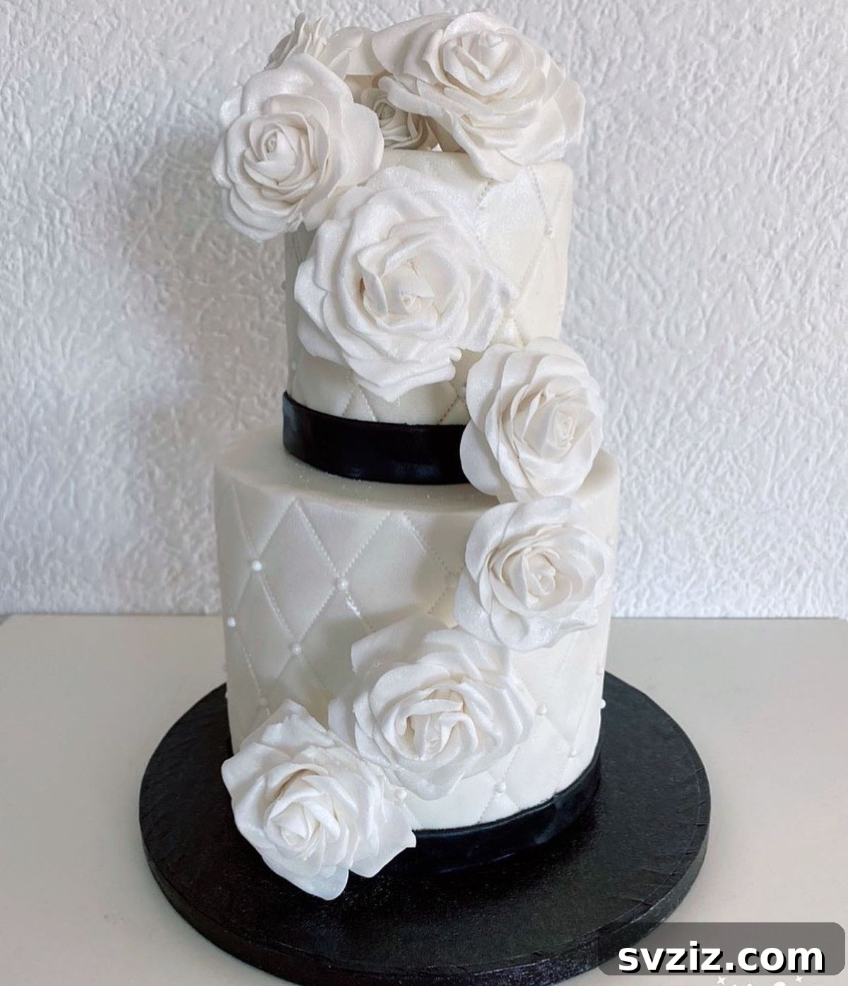 27 Elegant Wedding Cake Inspirations 25 A fabulous monochrome wedding cake featuring classic quilting and a show-stopping cascade of huge white roses from top to base, with vanilla sponge and Swiss meringue buttercream.
