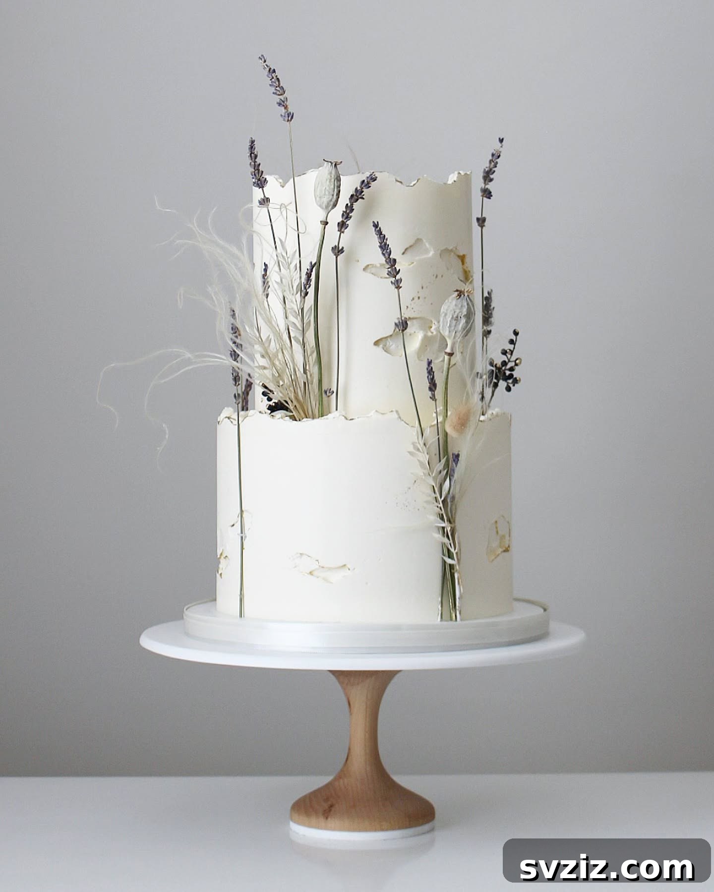 27 Elegant Wedding Cake Inspirations 27 A breathtaking rustic wedding cake with raw, unfinished edges, adorned with a burst of dried foliage, wisps of lavender, poppy seed pods, and airy grasses, creating an enchanted woodland theme.