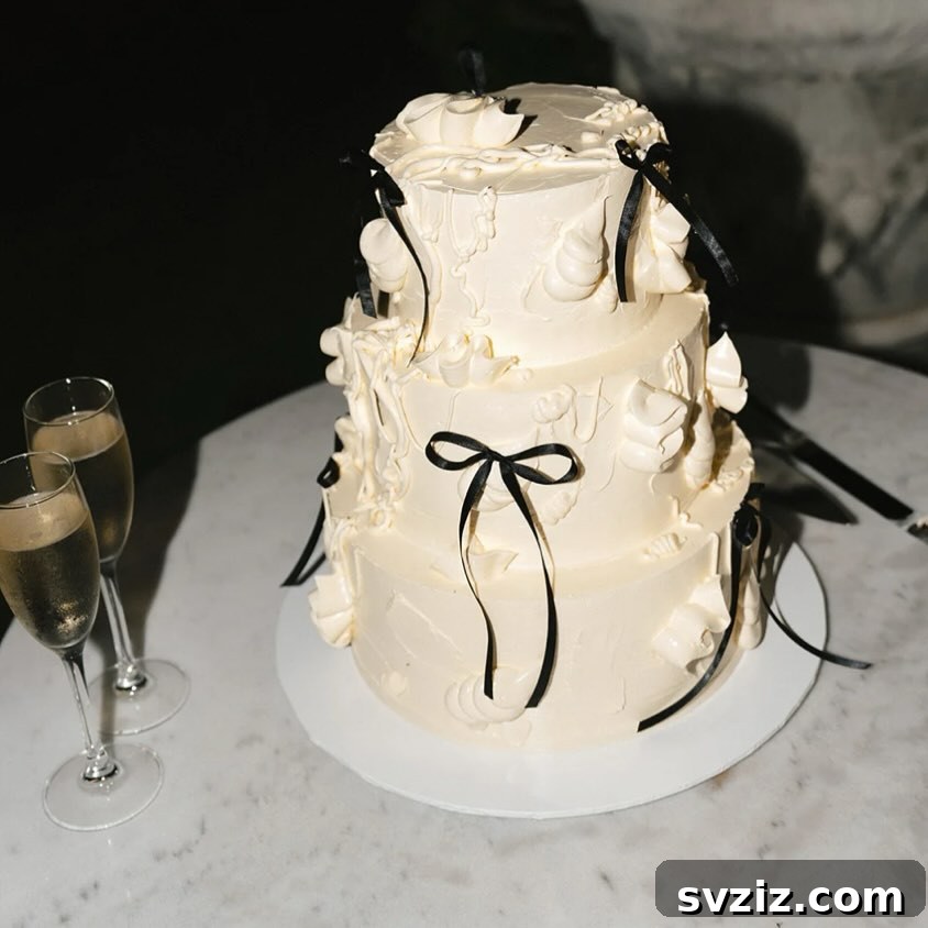 27 Elegant Wedding Cake Inspirations 6 A lavishly iced, ivory three-tier wedding cake adorned with stylish black bows, creating a chic, modern, and timeless contemporary twist for elegant celebrations.