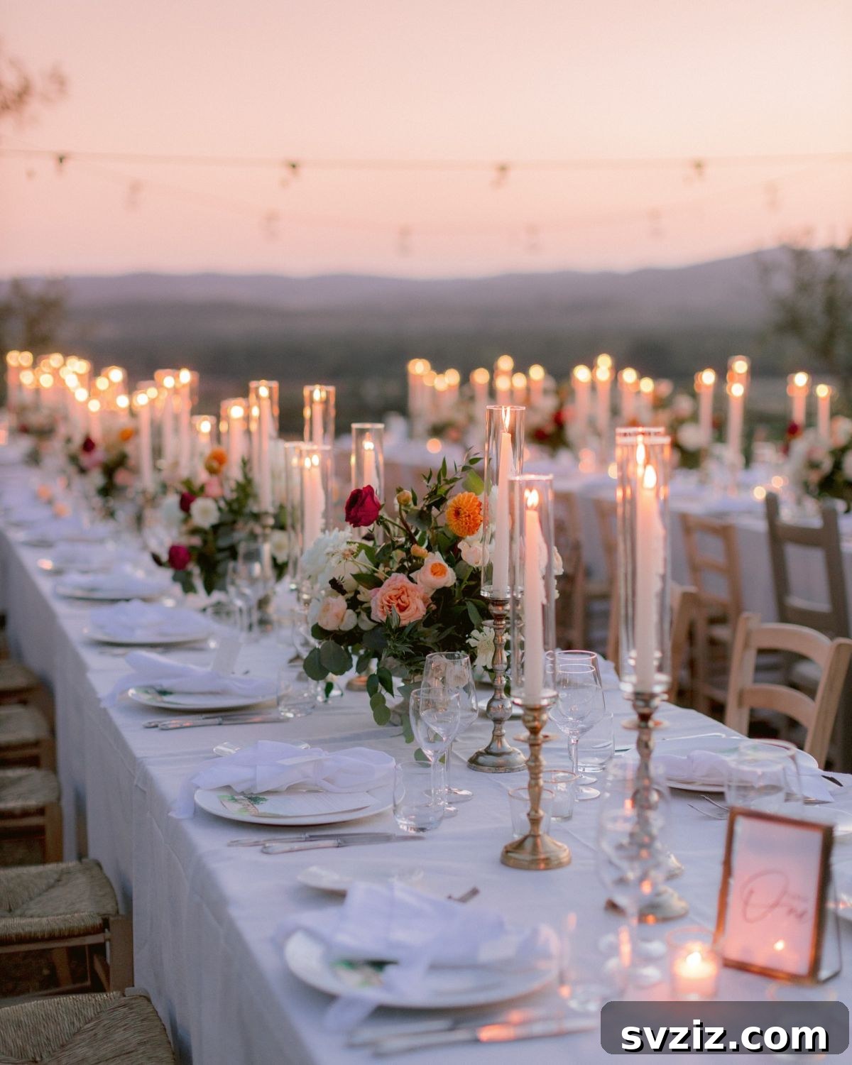Romantic wedding table setting illuminated by tall white taper candles in golden holders, creating a timeless ambiance.