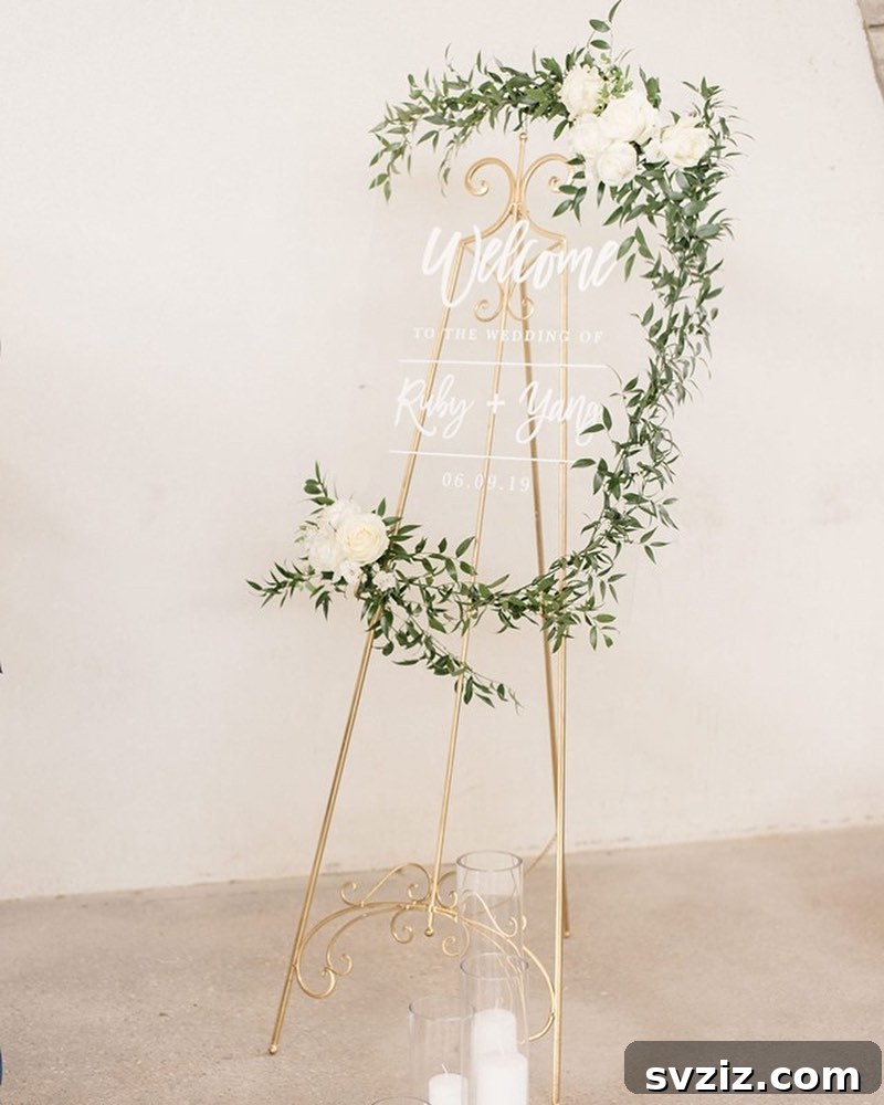 Golden elegance glass welcome sign with graceful white writing, framed by lush greenery and white roses.