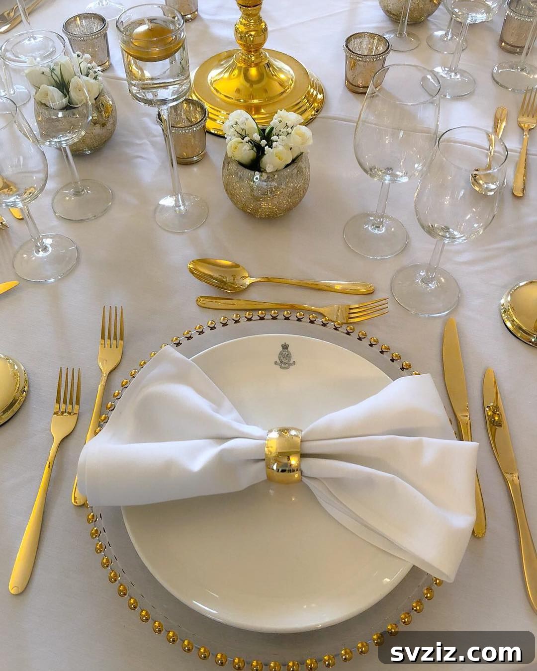 Luxurious royal gold and white wedding table setting with opulent cutlery, napkin rings, and charger plates.